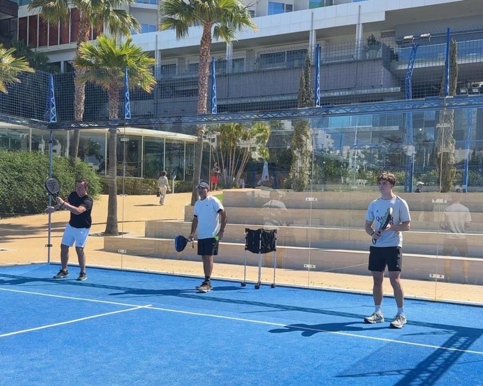 Three coaches standing together on a padel court in Spain